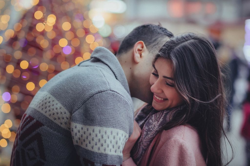 Young couple embracing infront of a Christmas tree downtown Toronto